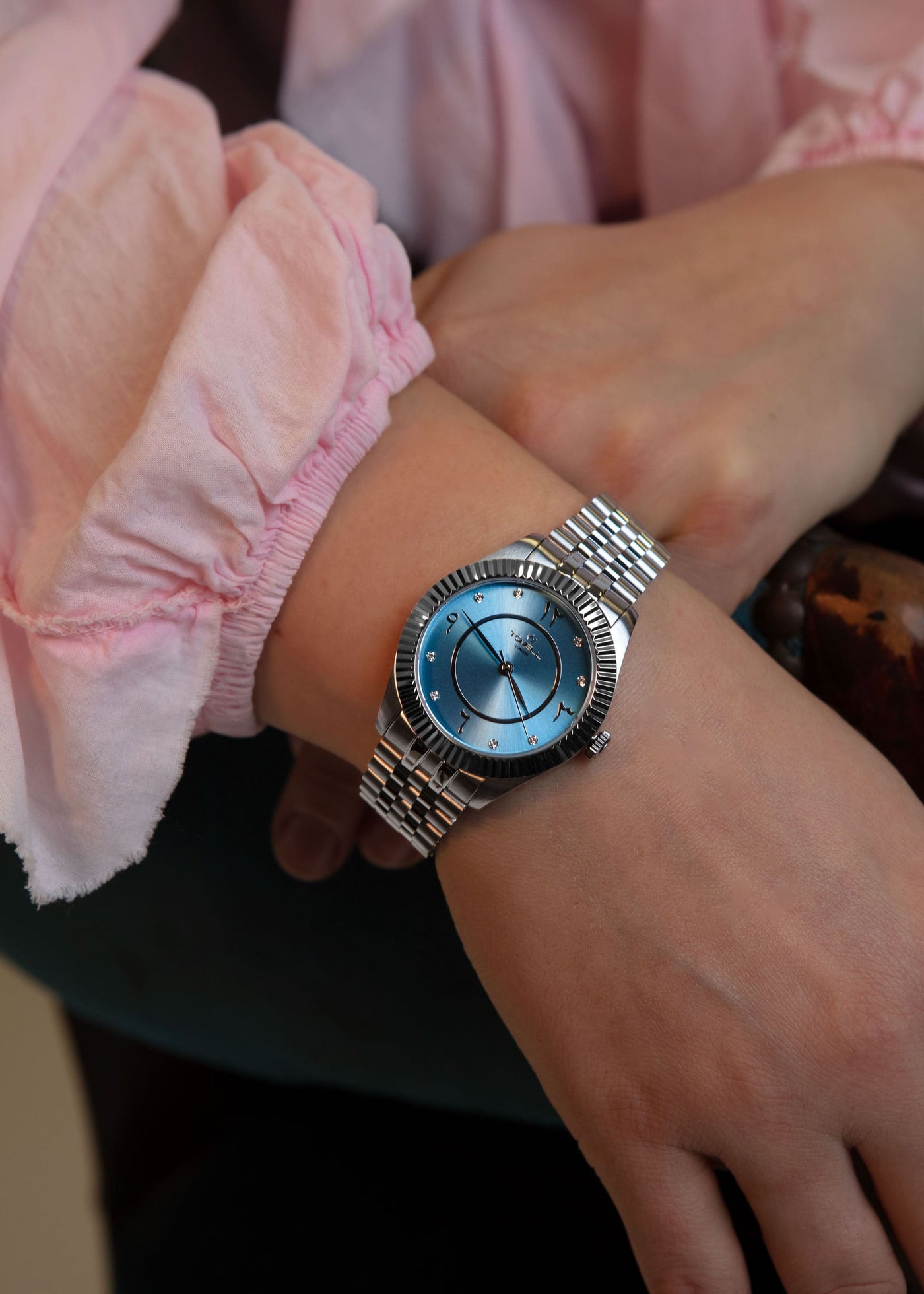 Silver watch on a wrist with pink sleeve