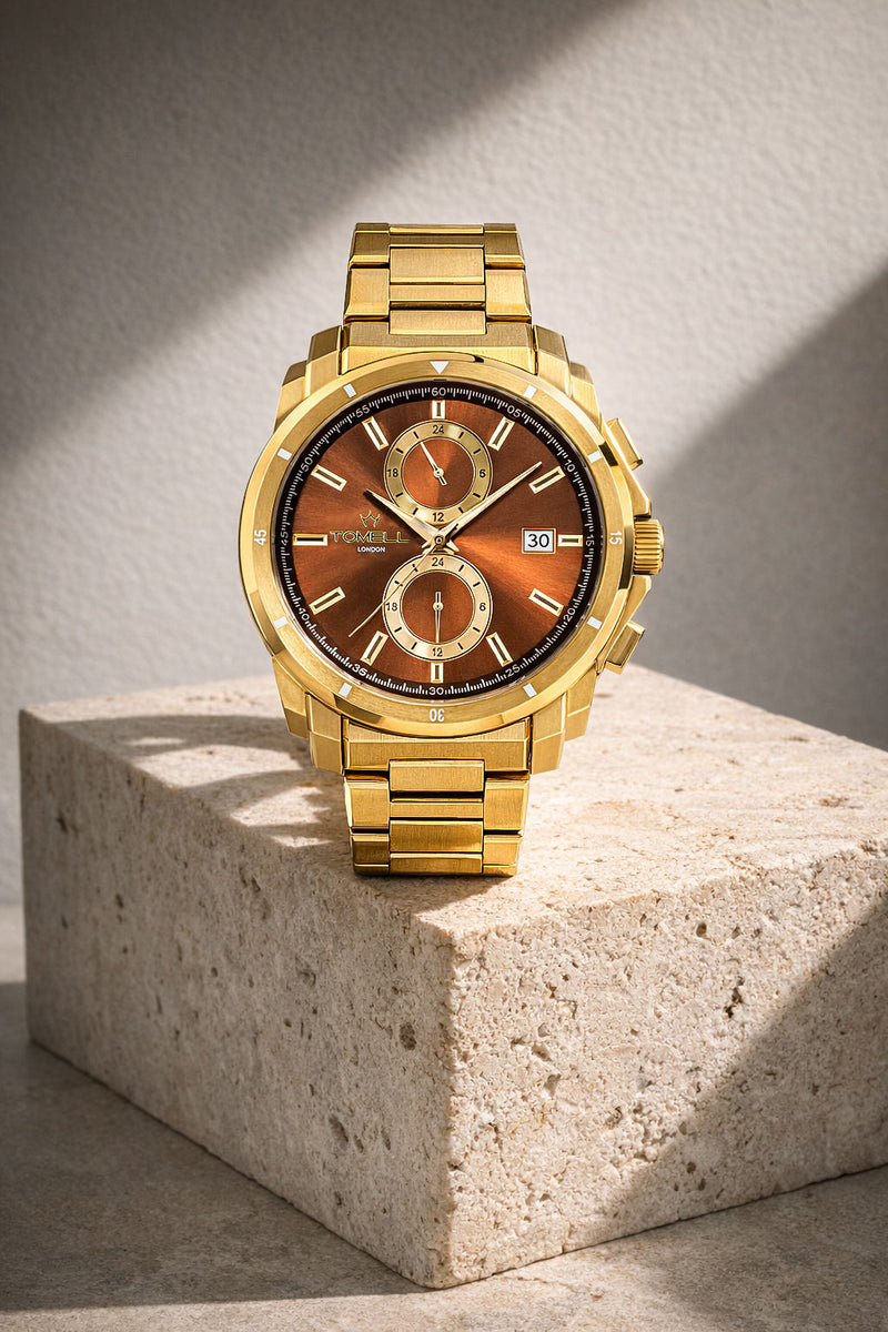 Gold wristwatch with a brown dial on a textured stone surface