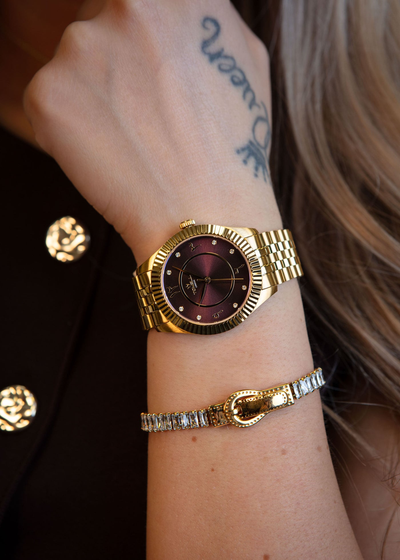 The unique gold watch with the aubergine dial presented next to its luxury packaging.