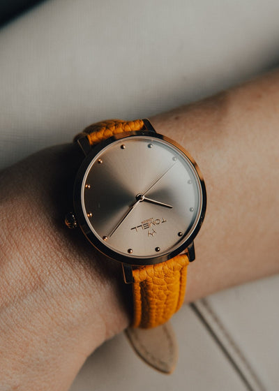 Wrist wearing a watch with a gold strap