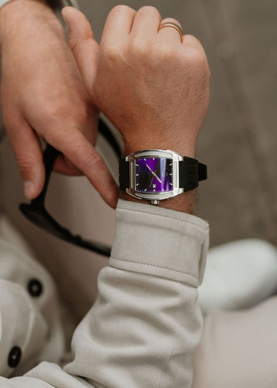 Person wearing a watch with a purple face 