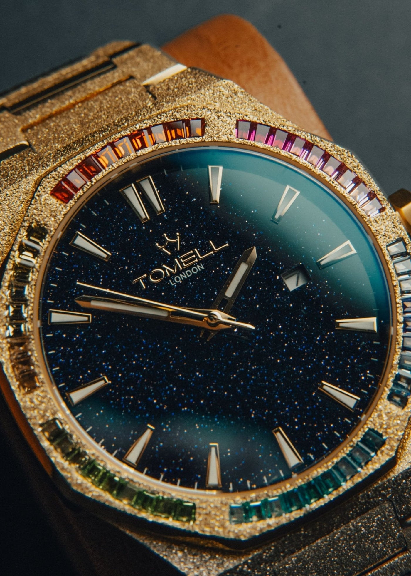 Luxury watch with gold casing, gemstone accents, and dark blue face.