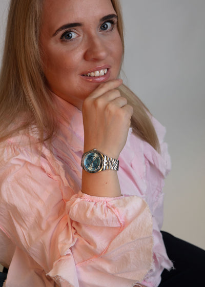 Stylish silver watch with blue dial worn on the wrist, showing the bracelet links and fit.