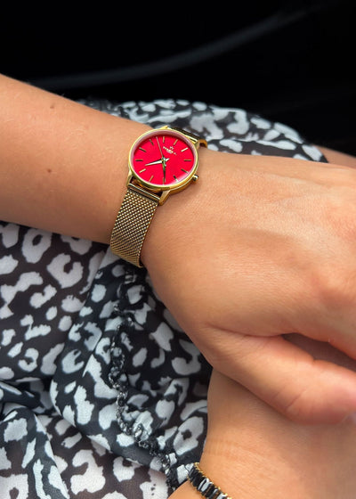 gold watch with red face and mesh strap 